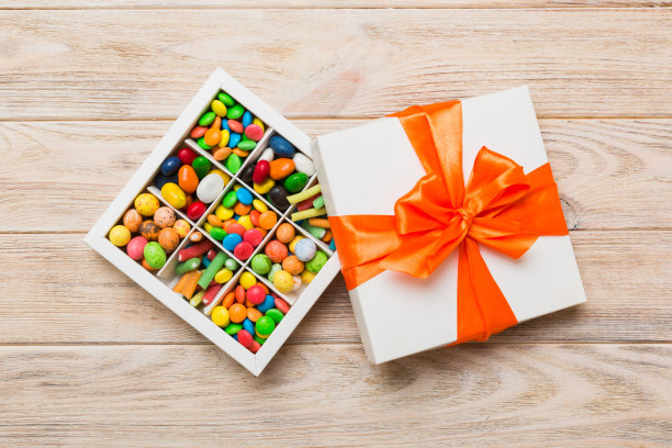 一套不同的糖果在一个纸盒与缎带彩色背景。节日的概念图片下载