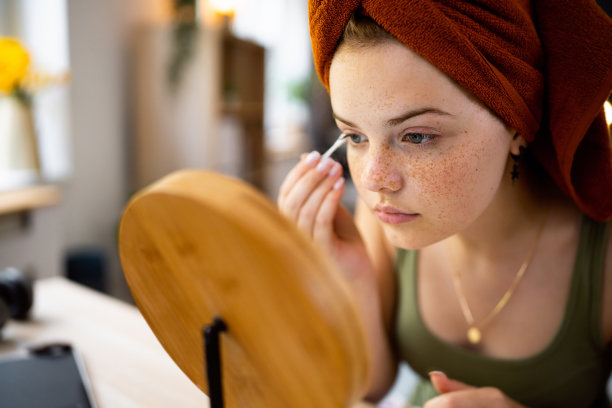 十几岁的女孩，用毛巾包着头发，在镜子前用棉签洗脸。图片下载
