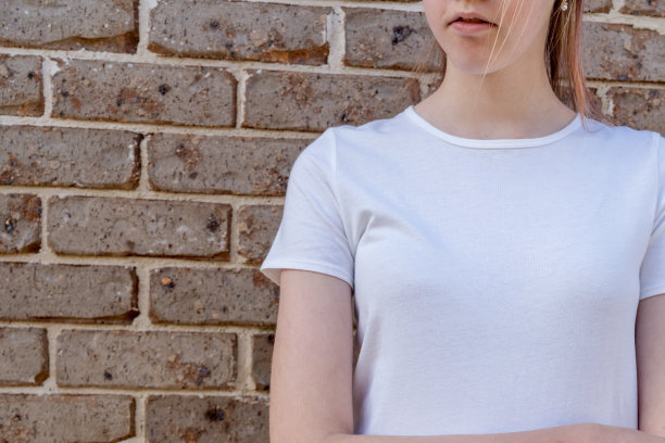 在砖墙背景上穿着白色t恤的女孩。模板复制空间图片下载