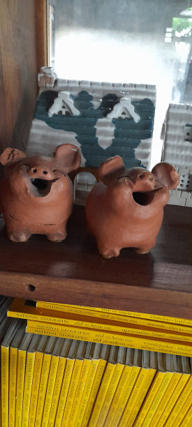 两只陶土做的小猪看起来很开心，有一个明亮的微笑。树干可以长树。图片下载