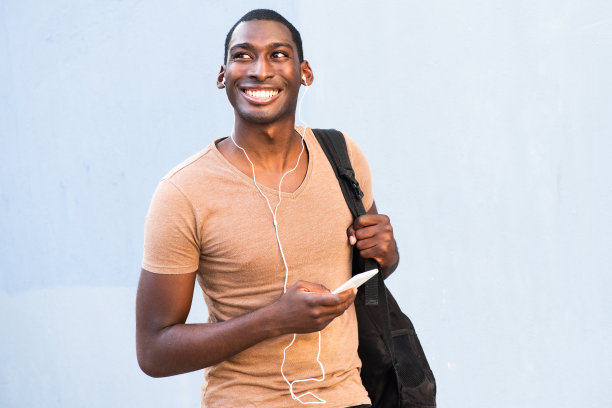 年轻英俊的黑人男子用手机和耳机听音乐图片下载