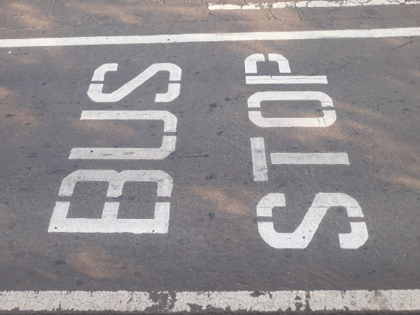 白色短短语文本词公交车站用线在城市柏油路公交车站前图片下载