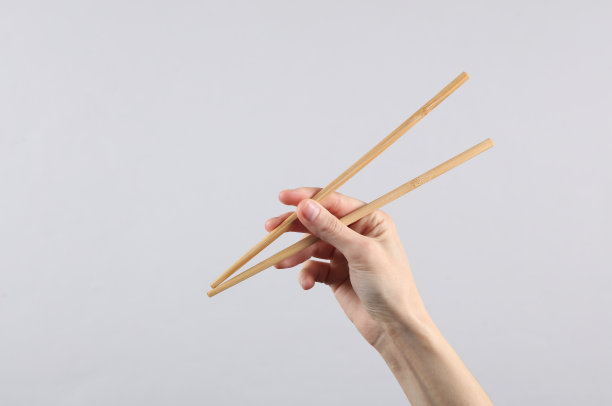 灰色背景上，一位女性手中的中国筷子图片下载
