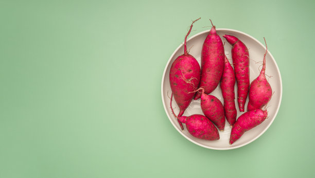白色盘子上的日本红薯，绿色背景图片下载