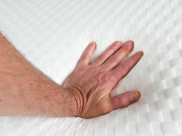 一个人在测试新床垫的柔软度。他的手微微下沉图片下载