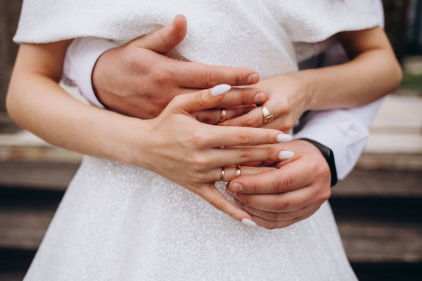 一男一女戴着结婚戒指的照片。年轻的新婚夫妇手牵着手，举行婚礼。新婚夫妇戴着结婚戒指的手。图片下载
