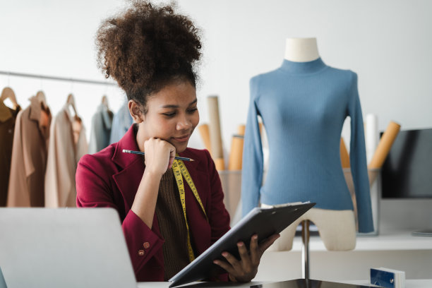 黑人女性，平板电脑和电子商务、时尚或物流领域的小企业，在家远程创业。非裔美国女老板在店里工作时想着衣服的颜色成功了图片下载