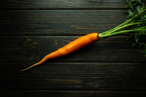 新鲜甜美的胡萝卜放在黑色木桌上，准备加入食物中。副本的空间。胡萝卜饮食理念图片下载
