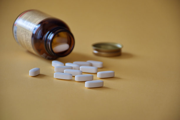 白色药丸从玻璃药瓶中溢出图片下载