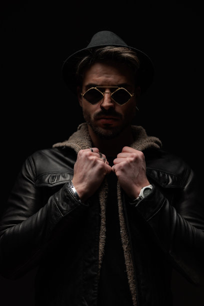酷酷的留着胡子的男人戴着墨镜拉羊毛开衫和皮夹克图片下载