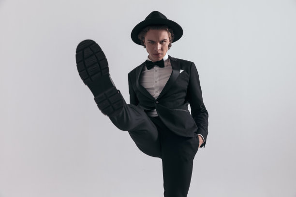 酷酷优雅的新郎穿着黑色燕尾服，双手插在口袋里，高举鞋底图片下载