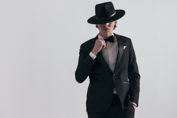 神秘的伴郎穿着燕尾服，系着领结，用帽子遮住眼睛图片下载