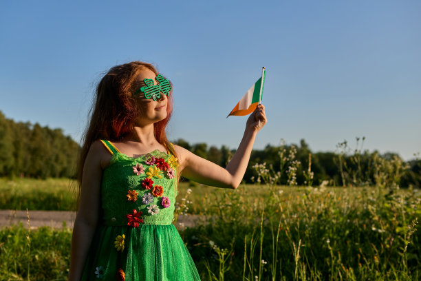 在圣帕特里克节，红发小女孩打扮成小妖精，挥舞着爱尔兰国旗图片下载