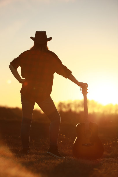 牛仔女郎在日落时弹吉他图片下载