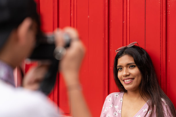 当一个男人在拍照时，注意一个年轻女人摆姿势的笑脸图片下载
