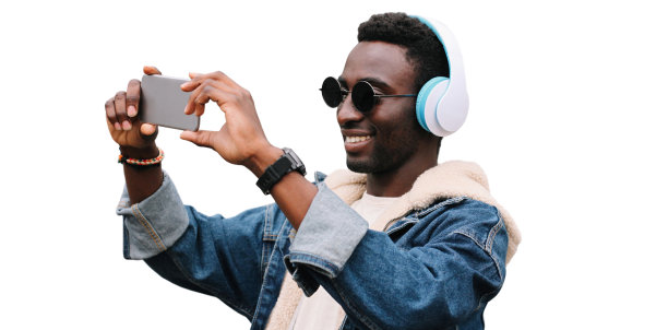 快乐微笑的非洲青年男子的肖像，用智能手机自拍，耳机听音乐，孤立在白色背景上图片下载
