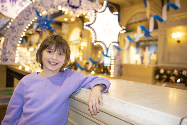 快乐的男孩在圣诞节装饰的购物中心的晚上图片下载