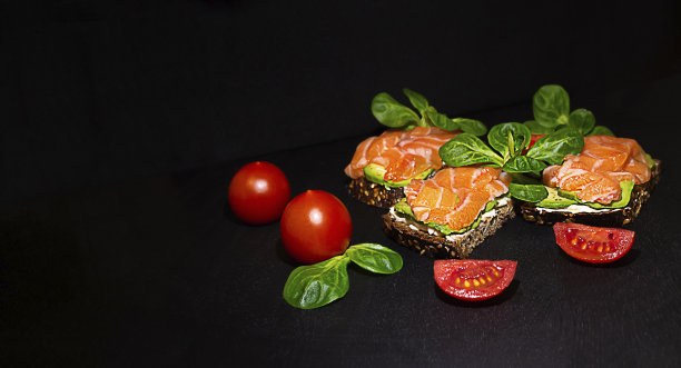 黑面包三明治，绿色牛油果，融化的红色鱼奶酪配绿色罗勒叶和红色圣女果，广告图片下载