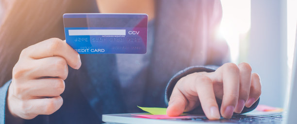 女性手持信用卡，用笔记本电脑在网上订购产品。图片下载