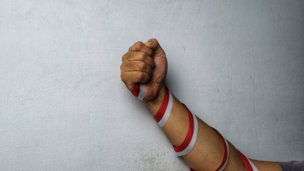 戴着红白丝带的手握拳图片下载