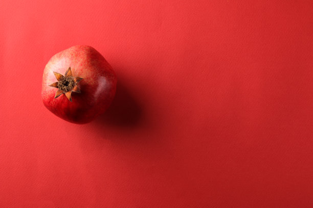 成熟美味的红石榴果在明亮的红纸背景。前视图。文本空间图片下载