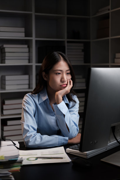 疲惫的年轻亚洲女商人在晚上加班时感到疲倦和失去注意力。图片下载