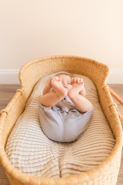 一个20周大的男婴躺在一个舒适的纱布毛毯里，躺在一个海草摩西篮子里图片下载