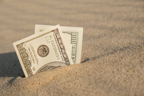 在沙滩上兑换美国百元美钞。概念理财为度假攒钱。旅游假期费用图片下载
