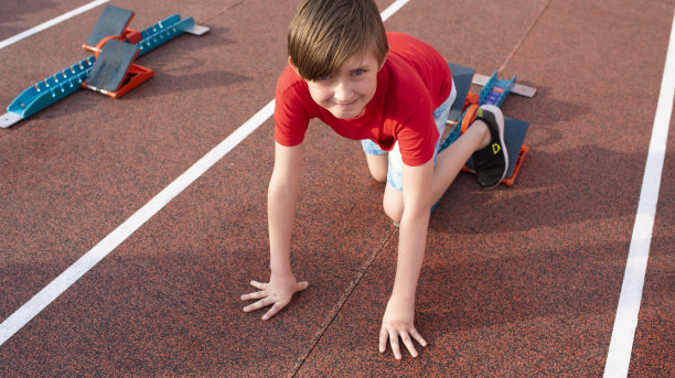 小男孩要开始跑了。一个10岁的孩子站在跑步机后面，等待比赛开始，准备出发。图片下载