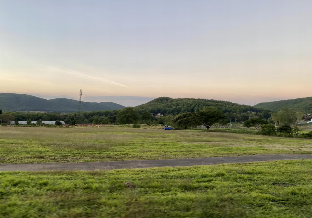 一张以田野为背景，有一条路和一座山的照片，远处是田野，有一条路和一座小房子。图片下载