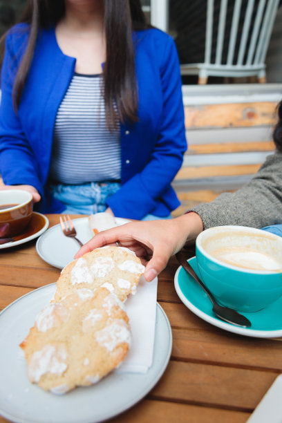 咖啡的乐趣:俯视图的年轻妇女喝咖啡和吃甜糕点在一个舒适的咖啡馆天井图片下载