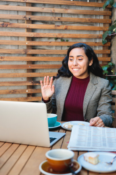 黑发拉丁女商人在一个热闹的咖啡馆设置出色的笔记本电脑视频通话图片下载