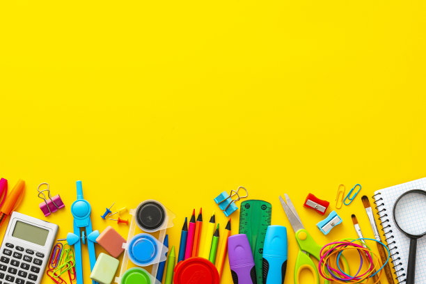 一大群五颜六色的学习用品排列在黄色背景的底部。副本的空间。图片下载