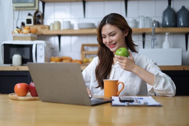 快乐的女人在家里用笔记本电脑工作。图片下载