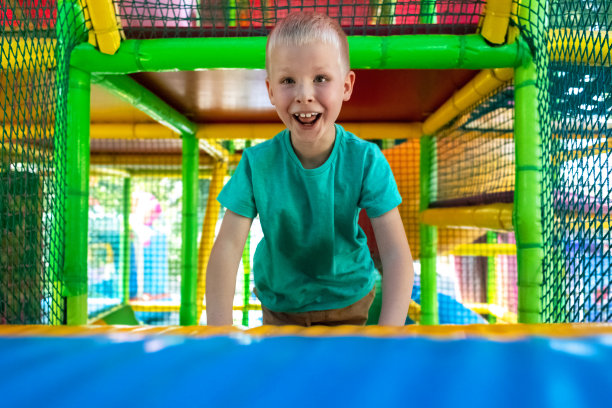 在游乐区玩耍的金发男孩的肖像。儿童迷宫。脸部特写，上面的情绪有幸福、有趣和粗心。小山，迷宫，蹦床。对儿童的安全吸引力图片下载