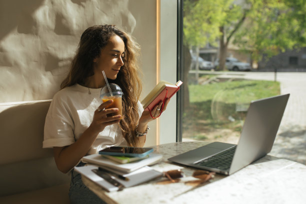 在咖啡馆工作的年轻自由职业者，使用她的笔记本电脑和智能手机。图片下载