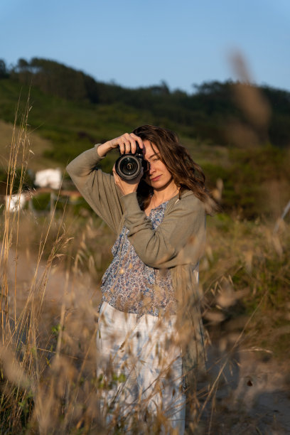 摄影师在夏天的海滩上用相机拍照，旅行者潮人拍摄日落景观，爱好度假概念图片下载