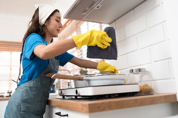 亚洲妇女穿着工作服女仆打扫家，用超细纤维布在厨房擦桌子图片下载