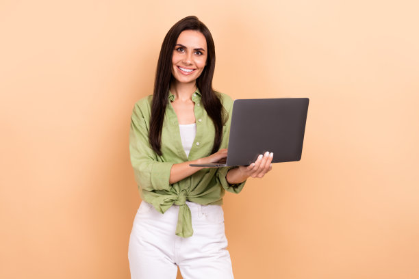 照片相当积极的招聘女孩牙齿微笑使用微软上网本孤立的米色背景图片下载