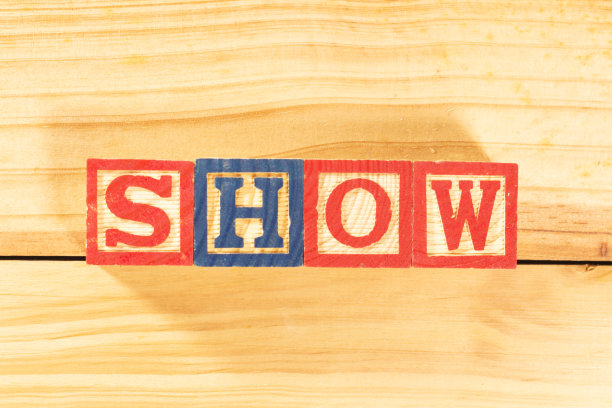 华丽的彩色字母在木板上的木制立方体上，上面写着“SHOW”这个词。图片下载