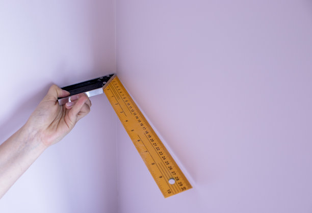 工人拿着量具，金属角，测量墙的角度。完成工作。公寓、办公室维修图片下载