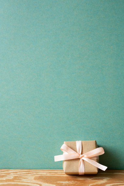 木制桌子上最小的棕色礼盒。绿色墙面背景。本空间图片下载