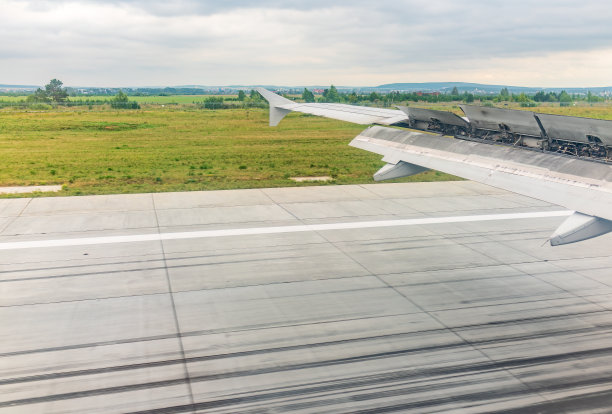 飞机机翼的视图，蓝天和绿色的土地在着陆。飞机窗口视图。图片下载