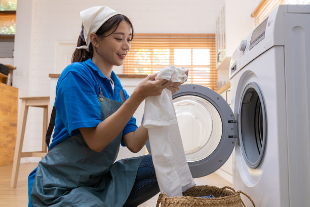 年轻的家庭主妇用自动洗衣机洗衣、烘干、纺纱。图片下载