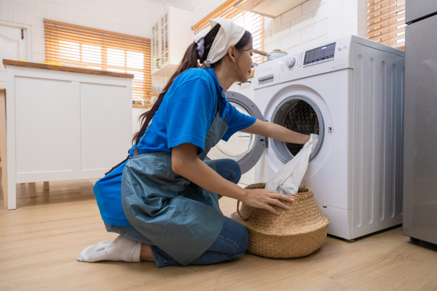 年轻的家庭主妇用自动洗衣机洗衣、烘干、纺纱。图片下载