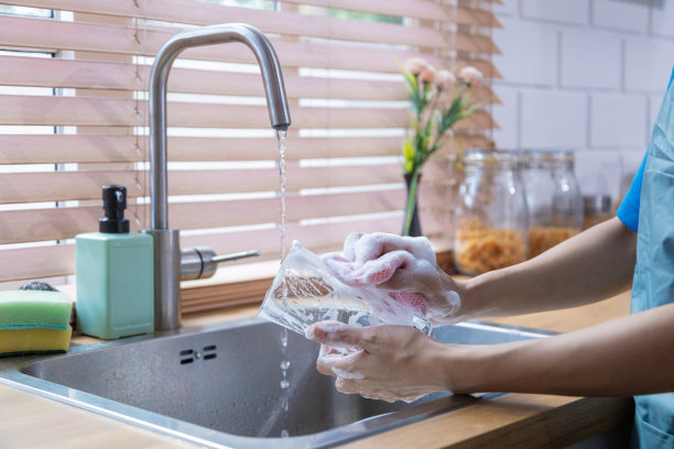 年轻的职业亚洲少女家庭主妇洗陶器和打扫房子。图片下载