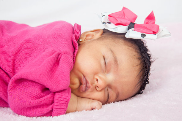 一个可爱的一个月小婴儿的特写，穿着粉红色的衣服，戴着蝴蝶结睡觉图片下载