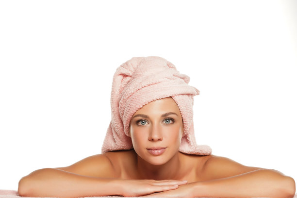 年轻的微笑的美丽的女人用毛巾在她的头上摆姿势图片下载