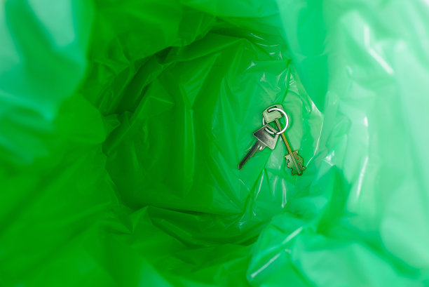 垃圾桶里的绿色垃圾袋。里面有一把公寓钥匙。前视图。图片下载