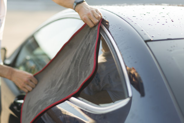 工人在洗车场洗车并用抹布擦车。图片下载